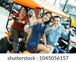 Small photo of Mature couple with two adult children sitting in grand tour electric and taking pictures of Europenian city