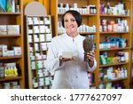Small photo of Portrait of positive female pharmacist with dried vulnerary plans in hands