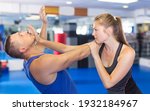 Small photo of Ordinary woman is fighting with trainer on the self-defense course for woman in sport club