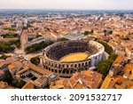 Aerial view of historical area of French city of Nimes overlooking restored antique Roman amphitheatre on sunny autumn day