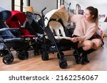Small photo of .Positive woman choosing carriage for kids in the children's store .