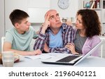 Small photo of Chagrined family with teenage son working with papers at home
