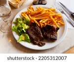 Small photo of Delicious hearty dinner of baked beef steaks served with crispy french fries and salad of fresh lettuce dressed with piquant hollandaise sauce..