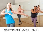 Small photo of Portrait of cheerful girl practicing vigorous jive movements in group dance class.