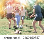 Small photo of Cheerful teen friends gaily spending time together on summer day, playing with ball outdoors