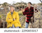 Small photo of Two angry casual women neighbors of different ages arguing during the vegetable garden season on sunny day of spring