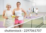 Small photo of Women with racquets and balls standing in pickleball court and looking at camera