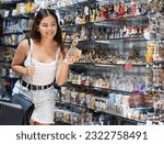 Small photo of Rapt young woman choosing Spanish dancer statuette among various souvenirs in gift shop in Barcelona