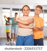 Small photo of European boy and girlie learn figures of pair dance and train before competition. Children fitness group is engaged in studio