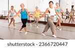 Small photo of Positive women practicing vigorous dance movements in group dance class