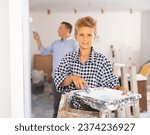 Small photo of Smiling boy standing at stepladder and holding paint roller. Youngster assisting with home improvement works.