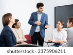 Young male tutor teaching students in college classroom