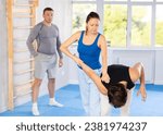 Small photo of Young guy and woman train technique of performing effective protection with wring hands during training in self-defense techniques. Lesson in presence of experienced instructor