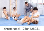 Small photo of Focused adolescent boys engaging in self-defense course, working on kimura maneuver in training bout under careful supervision of experienced trainer