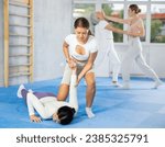Small photo of Young woman and girl train technique of performing effective protection with wring hands during training in self-defense techniques. Lesson in presence of experienced instructor