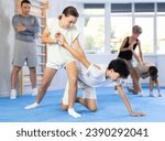 Small photo of Boys and girls train technique of performing protection with wring hands during training in self-defense techniques. Teenagers prepare for competition, under guidance of coach repeat combat skills