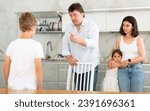 Small photo of At home in kitchen, parents scold son for imprudent act committed. Sulky schoolboy boy stands with arms crossed in front of, parents during serious conversation with boy Mom hugs daughter