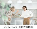Small photo of Two livid women brawling heatedly to each other in front of white kitchen cabinet