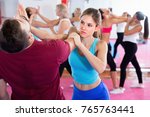 Glad cheerful positive smiling female is training self-defence moves in pair with trainer in sporty gym.