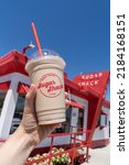 Small photo of Rudyard, Montana - July 2, 2022: Hand holds up a Sugar Shack diner chocolate milkshake from the retro throwback restaurant on the hi-line (or US-2)