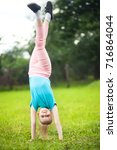 Small photo of Cute athletic scholar girl tumbling, turning, turn handsprings in the park, having fun. Sunny summer day. Sport for children. Kid doing gymnastic and having fun. Healthy body.