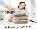 young businesswoman looking overwhelmed while surrounded by paperwork