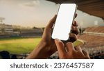 Small photo of Indian male fan using phone during cricket game on a stadium, making bet. Online bookmaker, making bets on the internet