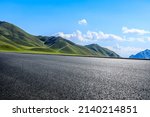 Empty asphalt road and green mountain under blue sky