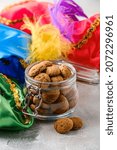 Small photo of Dutch holiday Sinterklaas traditional cookies kruidnoten in glass jar with colorful piet's berets. Pepernoten, traditional sweets, strooigoed. Concept of Saint Nicholas day.