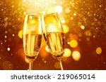 two glasses of champagne toasting against gold bokeh background