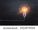 idea concept with innovation and inspiration, style symbol of creativity, brainstorm, creative idea, thinking. Lightbulb drawn by chalk representing ideas on dark background.