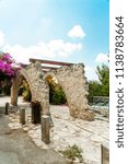 Small photo of Gazebo for wicker roses and flowers in the village of artists also composed of rough stones, but covered with wooden beams so that plants can keep on them creating a shadow