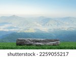 Small photo of Stone granite podium rock table top on green grass with outdoor mountain scene nature landscape at sunrise background.Natural organic beauty or healthy product placement presentation pedestal display.