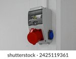 Small photo of Outdoor Electrical Box with Single and Three Phase Current Electrical Appliances and Power Outlets. Three phase connectors. In a factory hall, red and blue, 220 volt and 380 volt sockets.