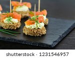 Smoked salmon canapes with cheese cream and dill on brown bread over black slate platter