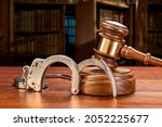 Small photo of A pair of handcuffs rests against a judge's gavel and block in a judge's law chamber. For inferences regarding public safety, crime, law and punishment. Copy space set aside on the upper left.