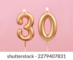 Burning golden birthday candles on pink background, number 30