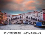  Famous Rialto bridge, early in the morning, with traditional gondolas, passenger transport boat (vaporettos) and cargo boat, on the Grand Canal in Venice, Italy