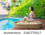 Portrait young asian woman happy smile enjoy with floating breakfast tray in swimming pool in hotel resort