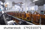 Small photo of Glass bottles filled with alcoholic beverages move along conveyor line with control panel in modern distillery for bottling alcoholic beverages. Factory for bottling prune tincture.