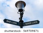 Street lighting pole with two opposite directional arrows over blue cloudy background. Bad Luck versus Good Luck concept.