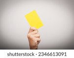 Small photo of the hand holds a yellow card as an attribute of punishment