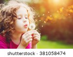 Little curly girl blowing dandelion.