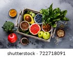 Healthy food clean eating selection in wooden box: fruit, vegetable, seeds, superfood, cereals, leaf vegetable on gray concrete background