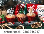 Homemade christmas muffins with fun Christmas signs and christmas decor ornaments on a tablecloth. Christmas sweet concept
