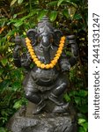 Small photo of Beautifully adorned Hindu Statuary decorated with flowers and offerings. Set amongst lush tropical gardens these statues provide solace and peace to Hindu worshipers.