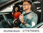 Small photo of Young multiracial couple sitting in a car and fastening seat belts.