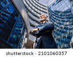 Successful and proud old executive. Low angle view of a proud senior businessman standing at the business center with arms crossed.