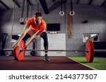 Small photo of A handsome man sets up a barbell with weights in a modern sports gym. Preparation for pumping muscles and burning muscles, cross-fit exercises. Active life, sports discipline