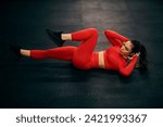 Small photo of A female athlete is doing knee to elbow crunches on a gym floor.